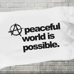 May include: A white poster with black text that reads "A peaceful world is possible." The poster has a black anarchy symbol in the upper left corner.