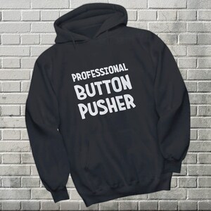 May include: Black hooded sweatshirt with the text "PROFESSIONAL BUTTON PUSHER" in white.