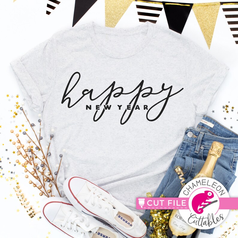 May include: A light gray t-shirt with the words "happy new year" in black script. The shirt is paired with blue jeans, white sneakers, and a champagne bottle. Gold and black party decorations are in the background.
