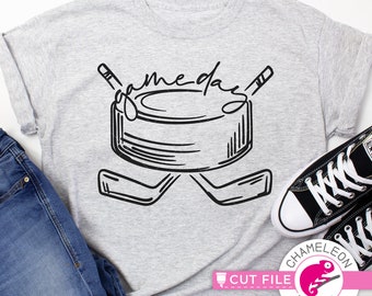 May include: A gray t-shirt with a black graphic of a hockey puck and two crossed hockey sticks. The text "game day" is written in a stylized font above the puck.