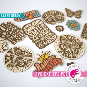 K&ouml;nnte beinhalten: Eine Sammlung von lasergeschnittenen Holzverzierungen im Retro-Stil. Designs umfassen Schmetterlinge, Blumen und S&auml;tze wie "Smile More Worry Less" und "Radiate Positivity". Die Farbpalette zeigt nat&uuml;rliche Holzt&ouml;ne mit Akzenten in Orange, Blau und Gelb.