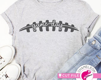 Puede incluir: Una camiseta gris con el texto "game day" escrito en cursiva negra sobre un contorno de balón de fútbol negro.