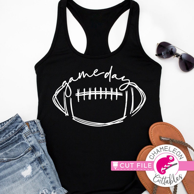 May include: Black racerback tank top with the words "gameday" and a football graphic in white. The tank top is paired with denim shorts, sunglasses, and sandals. A pink and white logo is in the bottom right corner.