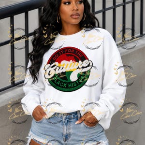 Può includere: Una felpa bianca a maniche lunghe con una grafica circolare sul petto. Il design include il testo "DO IT FOR THE CULTURE" e "BLACK HISTORY" nei colori rosso, giallo e verde, con la parola "Culture" in un carattere corsivo bianco.