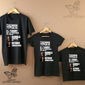 May include: Three black t-shirts with a graphic design featuring portraits of Rosa Parks, Ruby Bridges, Kamala Harris, and Ketanji Brown Jackson. The text reads "Rosa sat so Ruby could walk, so Kamala could run, so Ketanji could rule".