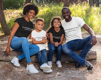 Könnte beinhalten: Eine vierköpfige Familie trägt passende T-Shirts mit dem Zitat "It is what it is - Michelle Obama" darauf. Die Familie sitzt auf einem Baumstamm in einem Waldgebiet.