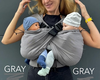 Puede incluir: Un portabebés doble gris con dos bolsas separadas para bebés, con correas y hebillas negras ajustables. El texto TWIN & SEPARATELY está impreso en blanco y verde claro, con la palabra GRAY impresa dos veces en blanco sobre la imagen.