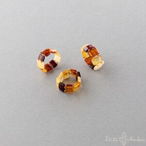 Puede incluir: Tres anillos de &aacute;mbar con un dise&ntilde;o cuadrado. Los anillos est&aacute;n hechos de diferentes tonos de &aacute;mbar, incluyendo amarillo, naranja y marr&oacute;n.