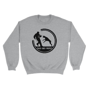 May include: A gray sweatshirt with a black silhouette of a person and a dog in a circle. The text "TRACK-OBEY-PROTECT" is below the circle.