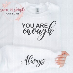 May include: White sweatshirt with black text that reads "You are enough Always" with a small heart symbol after each phrase.
