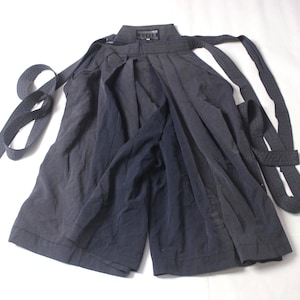 May include: Dark gray hakama pants with wide legs and attached waist ties. The traditional Japanese garment is made of a soft, flowing fabric. The pants are laid out on a white surface.