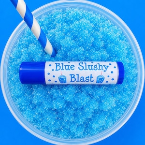 Peut inclure: Un récipient en plastique transparent rempli de slime bleu vif texturé, avec une paille rayée bleu et blanc et un tube de baume à lèvres étiqueté Blue Slushy Blast avec des graphismes de petits gobelets bleus sur fond bleu uni.