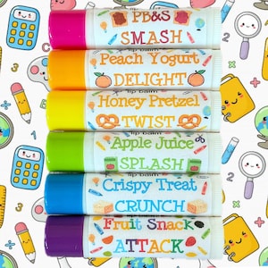 Könnte beinhalten: Sechs Lippenbalsam-Tuben mit farbenfrohen Kappen und Etiketten. Zu den Geschmacksrichtungen gehören "PB&S Smash", "Peach Yogurt Delight", "Honey Pretzel Twist", "Apple Juice Splash", "Crispy Treat Crunch" und "Fruit Snack Attack". Der Hintergrund zeigt Schulmotive.