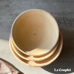 May include: Three round, light-colored proofing baskets of varying sizes, stacked on top of each other. The baskets have a spiral design and are labeled with measurements: 8 inches, 9 inches, and 10 inches. The brand name "La Couplet" is visible in the bottom right corner.