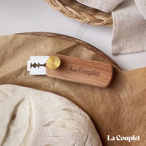May include: A wooden bread scoring tool with a brass knob and a razor blade. The tool is labelled "La Couplet".