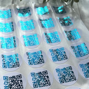 May include: A sheet of white paper with multiple round stickers featuring a blue and black QR code design.