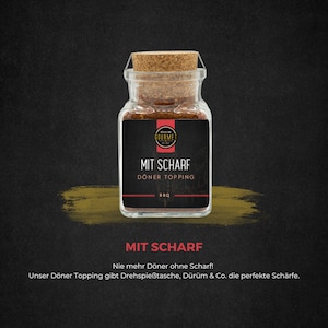 Könnte beinhalten: Ein Glasgefäß mit einem Korkverschluss, gefüllt mit roten und braunen Gewürzen. Das Etikett lautet "MIT SCHARF DÖNER TOPPING BBQ". Der Text unter dem Gefäß lautet "MIT SCHARF Nie mehr Döner ohne Scharf! Unser Döner Topping gibt Drehspießtasche, Dürüm & Co. die perfekte Schärfe."