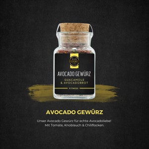 Könnte beinhalten: Ein Glasgefäß gefüllt mit einer roten und grünen Gewürzmischung. Das Etikett lautet "Avocado Gewürz" mit dem Text "Guacamole & Avocadobrot" und "Fitness" darunter. Das Gefäß befindet sich auf einem schwarzen Hintergrund mit einem gelben und goldenen Pinselstrich.