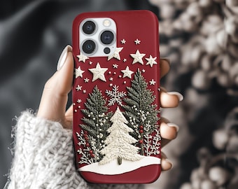 May include: A deep red smartphone case featuring an embroidered design of three evergreen trees, one white and two dark green, accented with red berries and white stars against a snowy base, with a camera cutout in the upper left corner.