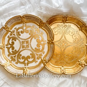 May include: Two decorative trays with ornate gold and white designs. The trays have a scalloped edge and are made of wood.