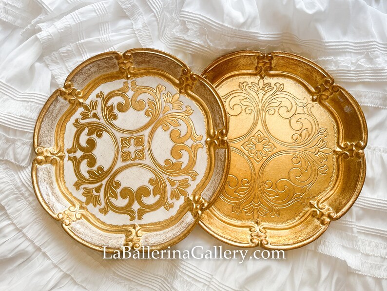 May include: Two decorative trays with ornate gold and white designs. The trays have a scalloped edge and are made of wood.