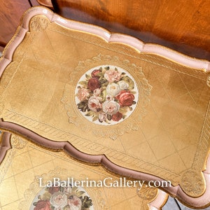 K&ouml;nnte beinhalten: Zwei dekorative Tabletts mit Goldoberfl&auml;chen und einem Blumenschmuck. Die Tabletts haben einen wellenf&ouml;rmigen Rand in Rosa und Gold, mit einem Blumendesign in der Mitte. Die Website-Adresse LaBallerinaGallery.com ist sichtbar.
