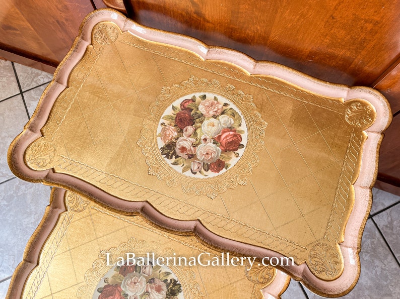 K&ouml;nnte beinhalten: Zwei dekorative Tabletts mit Goldoberfl&auml;chen und einem Blumenschmuck. Die Tabletts haben einen wellenf&ouml;rmigen Rand in Rosa und Gold, mit einem Blumendesign in der Mitte. Die Website-Adresse LaBallerinaGallery.com ist sichtbar.