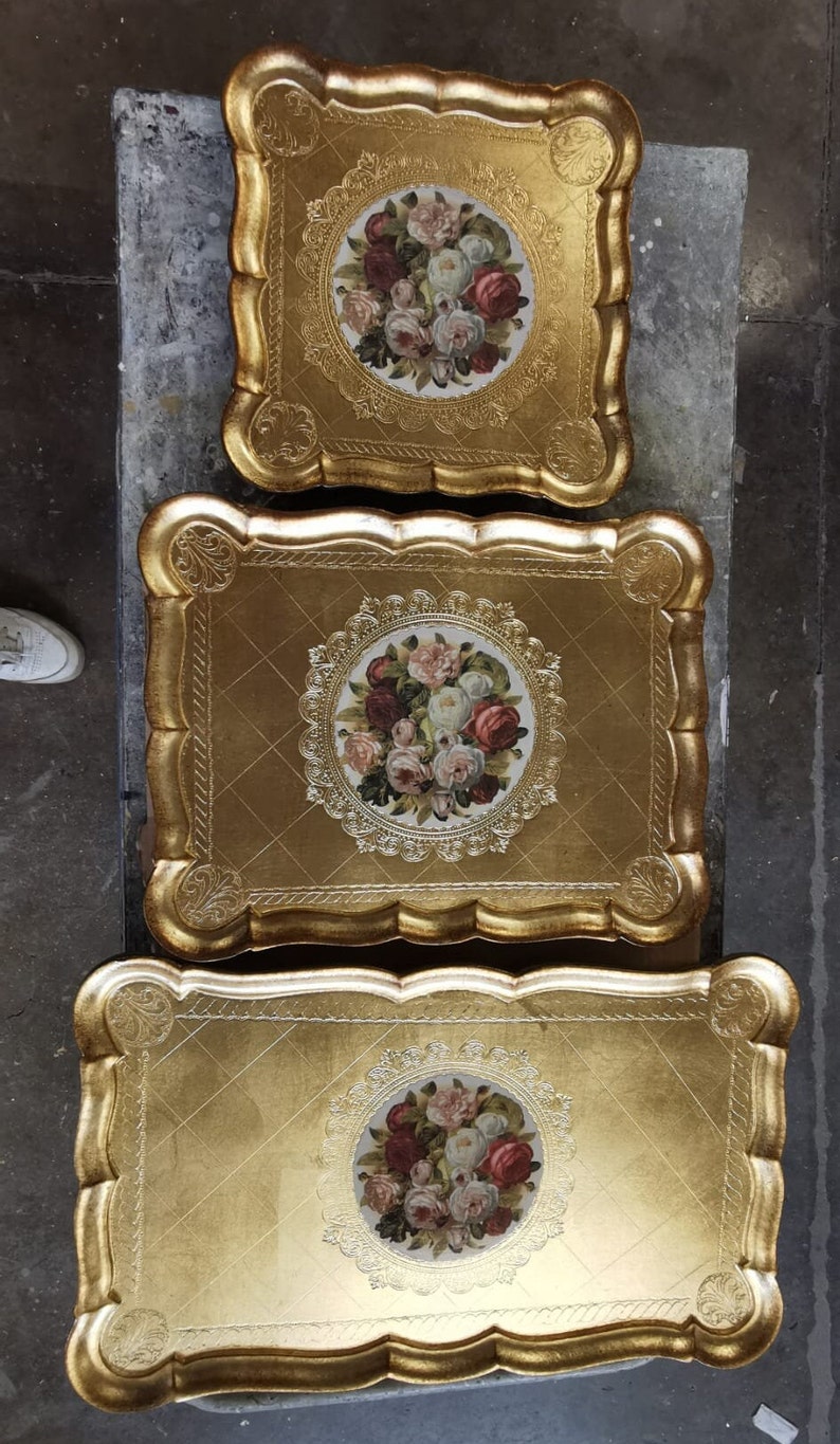 K&ouml;nnte beinhalten: Drei verzierte, goldfarbene Serviertabletts. Jedes Tablett hat einen gewellten Rand und ein Blumenzentrum mit roten, rosa und wei&szlig;en Rosen. Die Tabletts sind ineinander verschachtelt.