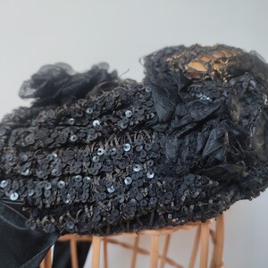 May include: A black hat with a large, ruffled bow and sequins. The hat is made of a soft, delicate fabric and has a vintage look.