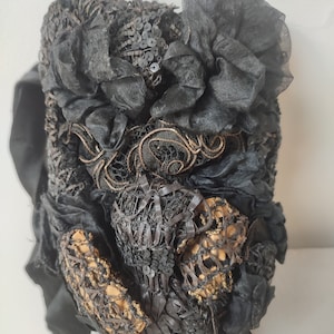May include: A black vintage hat with intricate lace and sequin details. The hat features a large black flower made of fabric.