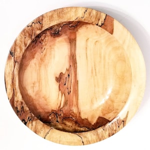 May include: A large, oval wooden bowl with a natural wood finish. The bowl has a light brown color with darker brown streaks and swirls throughout the wood grain. The bowl is empty and ready to be used.