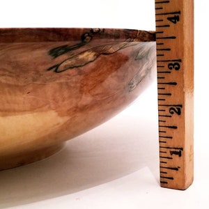 May include: A large wooden bowl with a natural wood grain pattern and a dark brown stain. The bowl is 3 inches tall and has a diameter of 12 inches.
