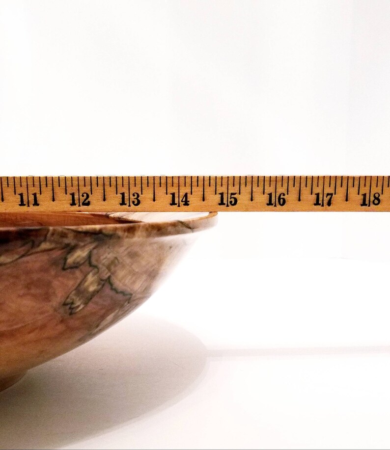 May include: A wooden bowl with a natural wood grain pattern. The bowl is 15 inches wide and has a light brown color.