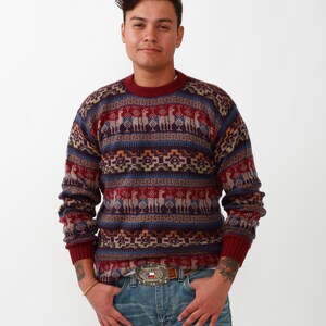 May include: A burgundy, blue, and beige patterned sweater with a crew neck and long sleeves. The sweater features a geometric design with llamas.