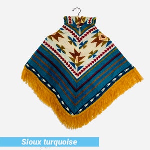 K&ouml;nnte beinhalten: Ein t&uuml;rkisfarbenes und braunes Poncho mit Fransenbesatz. Das Poncho hat ein geometrisches Muster mit einem Knopfverschluss am Hals.
