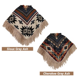 K&ouml;nnte beinhalten: Zwei gestrickte Ponchos mit Fransenbesatz. Der Poncho links ist wei&szlig; mit schwarzen, blauen und roten geometrischen Mustern und dem Text "Sioux Gray Ash". Der Poncho rechts ist grau mit schwarzen, blauen, roten und orangefarbenen geometrischen Mustern und dem Text "Cherokee Gray Ash".