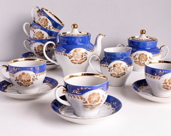 May include: A complete porcelain tea set featuring a teapot, sugar bowl, creamer, cups, and saucers. The set has a white base with blue accents and gold trim. Floral designs adorn the cups and other pieces, creating an elegant aesthetic.