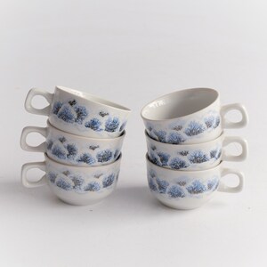 May include: Six white ceramic soup cups with handles. Each cup features a blue and gray tree design around the exterior. The cups are stacked in two groups of three, with a white background.