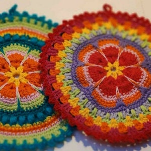 Può includere: Due coloratissimi sottopentola all'uncinetto fatti a mano. Uno è turchese, arancione e giallo, l'altro è rosso, viola e giallo. Entrambi hanno un motivo floreale al centro e un bordo smerlato. I sottopentola sono rotondi e hanno un anello per appenderli.