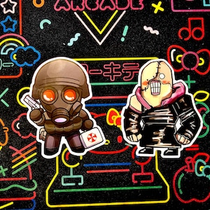 May include: Two cartoon stickers on a black background with neon lights. The sticker on the left is a character wearing a gas mask and holding a gun. The sticker on the right is a character with stitches on its face and a pink jacket.