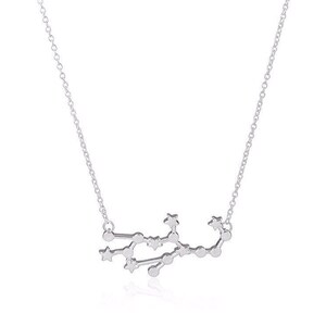 May include: A silver necklace with a delicate chain and a pendant shaped like the constellation Gemini. The pendant is made up of small, interconnected stars.
