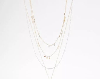 May include: A layered gold and silver necklace with a textured gold pendant. The necklace features small, round, clear and gold accents.