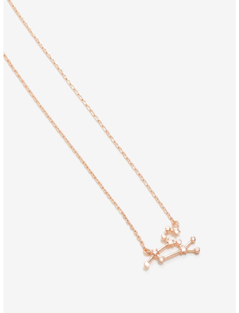 May include: A delicate rose gold necklace with a constellation pendant featuring a cluster of small sparkling stones. The necklace is a dainty and feminine piece of jewelry.