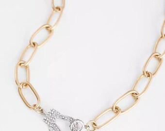 May include: A gold chain necklace with a silver clasp that is encrusted with clear rhinestones.
