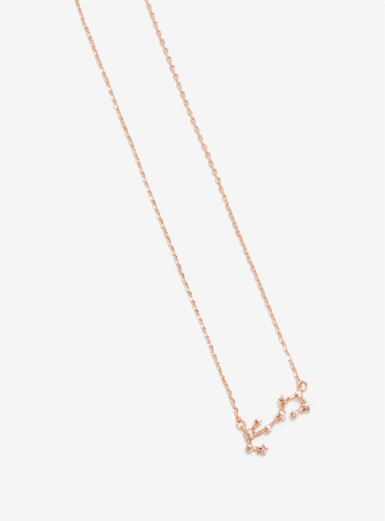 May include: A rose gold necklace with a delicate chain and a Sagittarius constellation pendant.