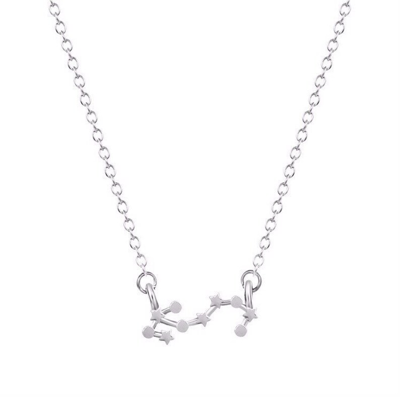 May include: A silver necklace with a delicate chain and a pendant shaped like the constellation Sagittarius.