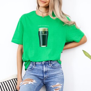 Puede incluir: Camiseta verde con el texto "Take Vitamin G" y un gr&aacute;fico de un vaso de cerveza Guinness.