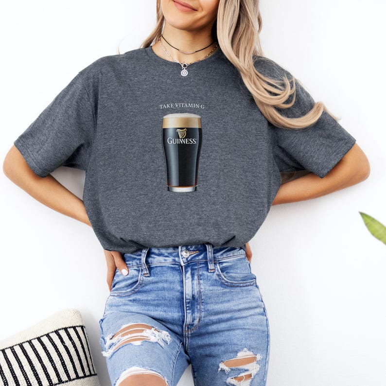 Puede incluir: Una camiseta gris oscuro con el texto "Take Vitamin G" y un vaso de cerveza Guinness impreso en la parte delantera.