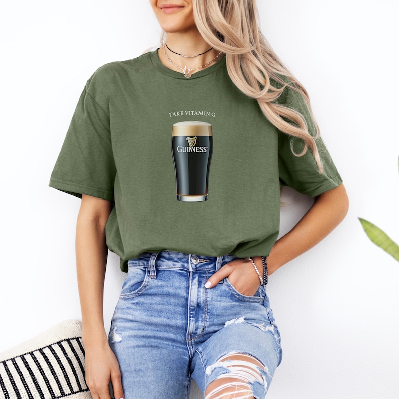 Puede incluir: Una mujer con una camiseta verde con el texto "Take Vitamin G" y un gr&aacute;fico de un vaso de cerveza Guinness.