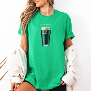 Puede incluir: Una camiseta verde con el texto "Take Vitamin G" y un gr&aacute;fico de un vaso de cerveza Guinness.